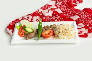 Turkish barbecues Sis lamb Kebab with rice and salad in a dish isolated on colorful table cloth top view on grey background photo