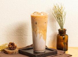 Iced Thick ginger milk tea served in disposable glass isolated on wooden board side view of taiwanese ice drink photo