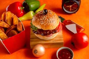 BBQ chicken cheese burger with french fries, potato and tomato slice isolated on wooden board side view on table fast food photo