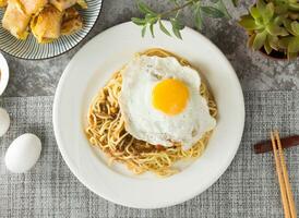 Black pepper sizzling noodles with sunny egg and chopsticks served in dish isolated on napkin top view on table taiwan food photo