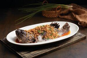 Steamed Dragon Tiger Grouper fish with Preserved Turnip served in a dish side view on dark background photo