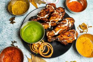 BBq chicken Tangri or tangdi with chili sauce served in a dish isolated on grey background top view of bangladesh food photo