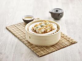 Scallops in Vermicelli Roll with Fried Garlic served in a wooden bowl side view on grey marble background photo