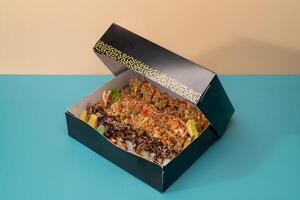 Mixed sushi platter served in a box isolated on blue background side view of japanese fast food photo