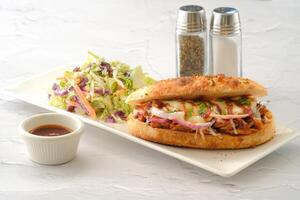 The Original BBQ Pulled Pork Sandwich with salad and chilli sauce served in a dish isolated on background side view of fastfood photo