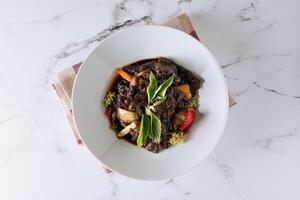 Black Pepper Beef with mushroom, tomato, onion in a dish isolated on mat top view on grey marble background photo