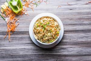 Hakka Noodles Vegetables with spoon and tissue isolated on wooden board top view on table fastfood photo