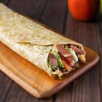 Beef Bacon Wrap paratha roll served in wooden board side view of indian fastfood photo