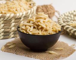 Almond sticks served in a bowl isolated on napkin side view of nuts on grey background photo