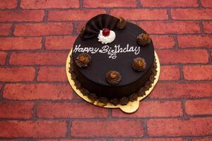 Chocolate cake topping with happy birthday writing served in plate isolated on background top view of bangladeshi dessert food photo
