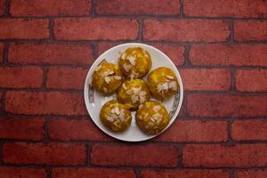 Mawa Laddu sweet topping with almonds served in plate isolated on background top view of bangladeshi dessert food photo