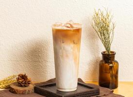 Iced Brown sugar milk tea served in disposable glass isolated on wooden board side view of taiwanese ice drink photo