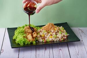 Traditional chinese food Fried Rice Yang Zhou with Abalone Mushroom and Teriyaki Sauce in black tray on wood table background photo