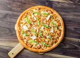 Chicken Fajita Pizza isolated on wooden background, spiced chicken cubes and cheese combination on bread, Italian food top view photo