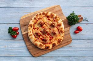 Italian meatballs pizza with tomatoes on cutting board wooden table background top view photo