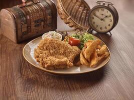 crujiente pollo chuleta con papas fritas en un plato aislado en oscuro de madera mesa lado ver Singapur comida foto