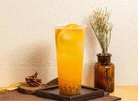 Korean Iced pomelo fruit tea served in disposable glass isolated on wooden board side view of taiwanese ice drink photo