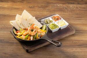 Mexican prawn fajita with bell peppers, grilled vegetables and onions top view on dark wooden background photo