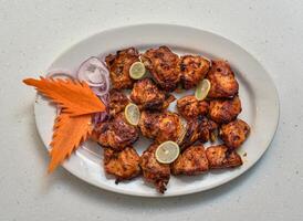 picante barbacoa pollo tikka bota kabab servido en un plato aislado en gris antecedentes parte superior ver de indio, pakistaní comida foto