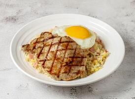 spanish pork chop steak with sunny side up egg and fried rice served in dish isolated grey background top view singapore fast food photo