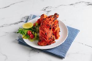 indian culture Tandoori chicken with lime in a dish isolated on napkin side view on grey background photo