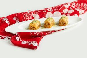 Turkish dessert baklava in a dish isolated on colorful table cloth top view on grey background Central Asian layered dessert photo