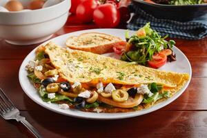 Mediterranean omelette roll with salad served in a dish isolated on wooden background side view photo