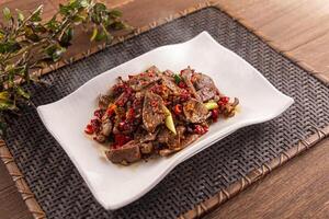 Spicy Stir-fried Pork Liver served dish isolated on wooden table top view of Hong Kong food photo