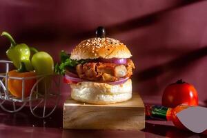 Chicken burger with tomato, ketchup and green chilli isolated on wooden board side view of american fast food photo