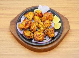 Spicy bbq chicken tikka boti kabab with lemon and onion served in a dish isolated on grey background side view of indian, pakistani food photo