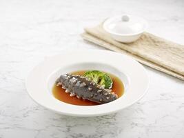 Braised Japanese Sea Cucumber in Oyster Sauce served in a dish side view on grey background photo