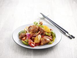 Sweet and Sour Pork with chopsticks served in a dish isolated on mat side view on grey background photo