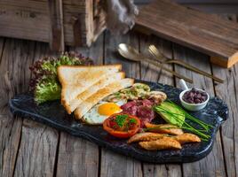 english breakfast with bread, beans, toast, egg, tomato served in a dish isolated on cutting board side view of breakfast on wooden background photo