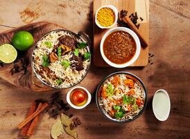 Indian spicy Lamb Shank Biryani, Butter Chicken Biryani with gravy, lime raita and gulab jamun Served in a dish side view on grey background photo