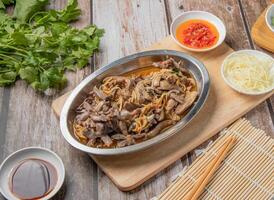 Pork and squid noodles water with chilli sauce, noodles, spoon and chopsticks served in dish isolated on napkin top view of hong kong food photo