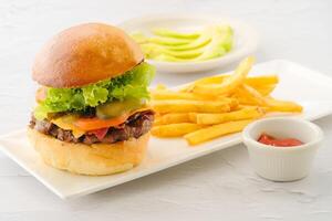 Signature beef Burger with fries and ketchup served in a dish isolated on background side view of fastfood photo