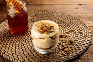 BAKLAVA served in a cup garnished with almond, pistachio and honey isolated on wooden background side view dessert photo