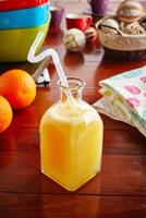 A jar of healthy fresh orange juice with straw isolated on wooden background side view photo