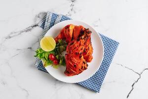 indian culture Tandoori chicken with lime in a dish isolated on napkin side view on grey background photo