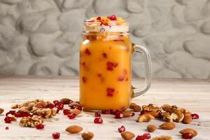 mango juice with nuts, pomegranate seeds, walnut, almond and cashew served in jar isolated on background top view of healthy morning drink photo