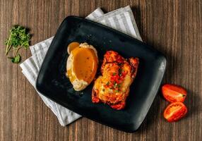 Slices of tasty Tex Mex Grilled Chicken Fajitas served in black tray on dark wood table top view food photo