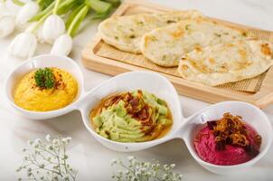 TRIO HUMMOS with pita bread served in a dish isolated on table side view of arabian food photo