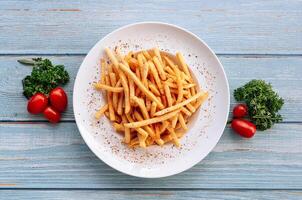 salty Caju Flavored Fries in white plate with tomatoes on wood table top view photo