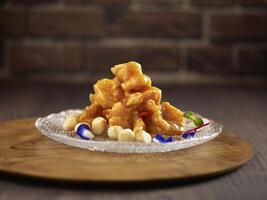 Crystal Prawns Tossed with Salad Sauce, Macadamia Nuts and Ebiko served in a dish isolated on cutting board side view on dark background photo