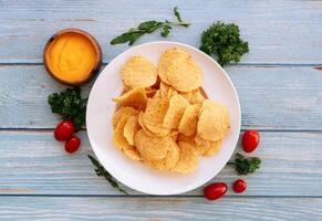 Crispy Nacho With Spicy Cheese dip in a white plate. Traditional fast food on wooden background top view photo