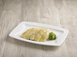 Steamed Kampong Chicken in Canton Style Served in a dish isolated on wooden board side view on grey background photo