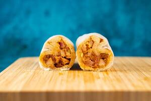 Chicken shawarma roll wrap isolated on wooden board side view of fastfood photo