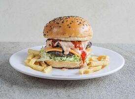 clásico carne de vaca hamburguesa con papas fritas servido en un plato aislado en gris antecedentes lado ver de rápido comida foto