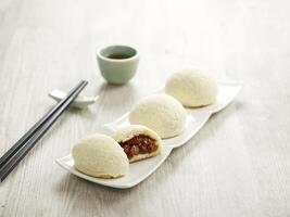 Baked BBQ Honey Pork Bun served in a tray with chopsticks isolated on mat side view on grey marble background photo