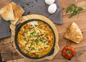 Tomato frying pan with eggs and cheese served in dish isolated on table side view of arabic food photo